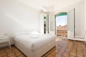 a white bedroom with a bed and a large window at Barnapartments Basic Gracia in Barcelona