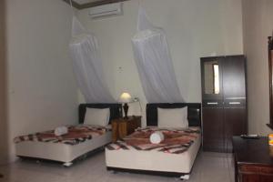 2 camas en una habitación con cortinas en BANYU URIP ROOMS, en Kuta Lombok