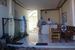 dos personas de pie en un mostrador en una habitación con tablas de surf en BANYU URIP ROOMS, en Kuta Lombok