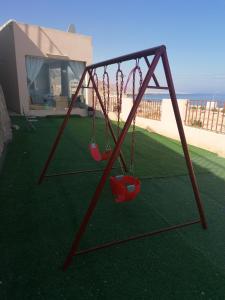 two swings in a yard with a house at Alshumukh guesthouse in Al Ghalīlah