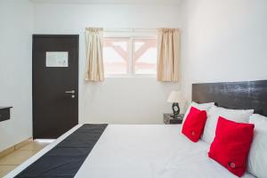 a bedroom with a white bed with red pillows at Hotel Nukuch Nah in San Cristóbal de Las Casas