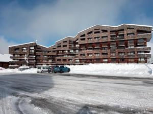 ein großes Gebäude, vor dem Autos parken in der Unterkunft Studio au pied des pistes- Le Praz de Lys in Taninges