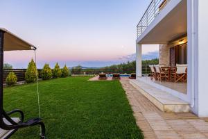 un cortile con patio e prato di Dimokritos Villas, a homestay experience, By ThinkVilla ad Angelianá