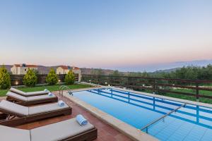 a swimming pool with a view of a house at Dimokritos Villas, a homestay experience, By ThinkVilla in Angeliana