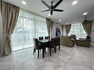 una sala da pranzo con ventilatore a soffitto, tavolo e sedie di Langkawi Cozy Holiday Home at Taman Indah by Zervin a Kuah