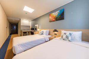 Cette chambre comprend 2 lits et une télévision murale. dans l'établissement Days Hotel & Suites by Wyndham Incheon Airport, à Incheon