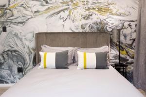 a bed with pillows in front of a wall at Melville Gap Guesthouse in Johannesburg