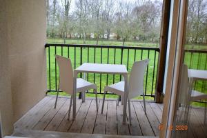 una mesa y sillas en un porche con vistas a un campo en Résidence les hauts de Honfleur, en Équemauville