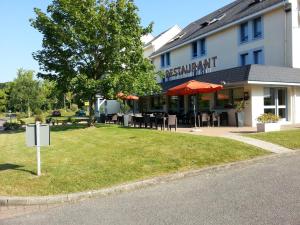 un restaurante con mesas y sillas frente a un edificio en KYRIAD ROUEN NORD - Mont Saint Aignan, en Mont-Saint-Aignan