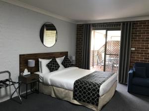 a hotel room with a bed and a balcony at Coffs Shearwater Motel in Coffs Harbour