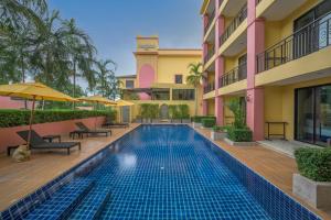 a swimming pool with chairs and umbrellas next to a building at Anchanlina Hotel - SHA Plus in Chalong 