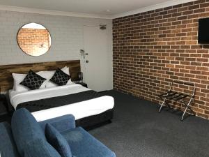 a bedroom with a bed and a brick wall at Coffs Shearwater Motel in Coffs Harbour