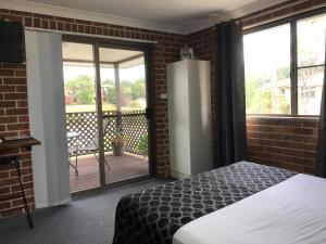 a bedroom with a bed and a balcony at Coffs Shearwater Motel in Coffs Harbour