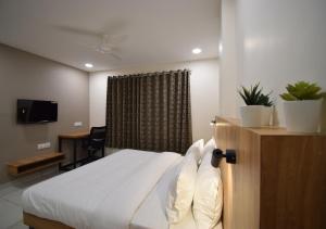 a bedroom with a bed and a desk and a television at Hotel Blue Bells in Indore