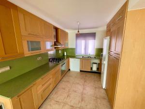 una cocina con armarios de madera y encimeras verdes en Royal Beach House Vista Mar, en La Mata