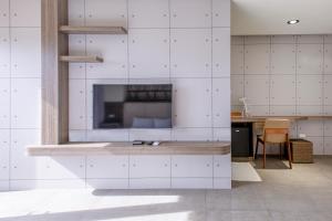 een keuken met witte betegelde muren en een grote tv bij Sharp B&B in Magong