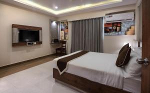 a bedroom with a bed and a flat screen tv at Hotel Monarch By Rivido, Bannerghatta Main Road in Bangalore