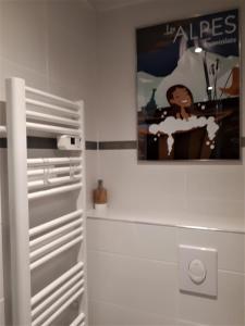 uma casa de banho com um cartaz na parede e um frigorífico em Pensée Des Alpes 2 Etoiles Ski and Spa em Brides-les-Bains
