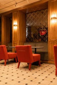 eine Lobby mit roten Stühlen, einem Tisch und einer Theke in der Unterkunft Potocki Boutique Hotel in Chmelnyzkyj