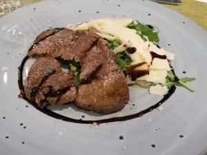 un piatto di cibo con carne e insalata sopra di Sicilia Hotel Spa a Giarre