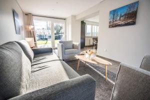 een woonkamer met een bank, twee stoelen en een tafel bij Salicorne Villa rénovée à l'orée de la zone naturelle in Groffliers