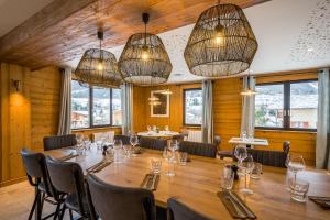 un comedor con una gran mesa de madera y lámparas de araña en L'Outa Hotel Restaurant, en Termignon