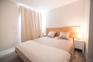 een witte slaapkamer met een bed en een nachtkastje bij Salicorne Villa rénovée à l'orée de la zone naturelle in Groffliers