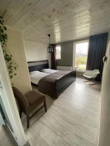 a bedroom with a bed and a chair and a window at Groepsverblijf "De Klosse" in Wanneperveen