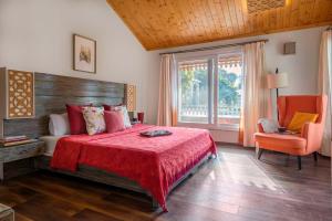 a bedroom with a bed and a chair and a window at StayVista at Dudly Manor with Swimming Pool in Dehradun