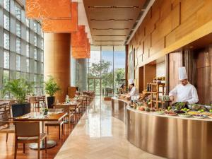 um restaurante com chefs a preparar comida numa cafetaria em Novotel Citygate Hong Kong em Hong Kong