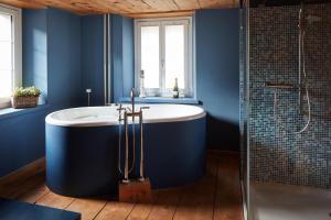 y baño azul con bañera y ducha. en Nostalgie Bed & Breakfast Chrämerhus, en Curaglia