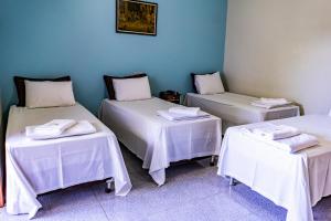 three beds in a room with white tables at Pousada Paraiso in Guanambi