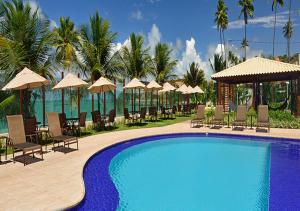 a swimming pool with chairs and umbrellas at a resort at Luxor Tabatinga Beira Mar in Conde