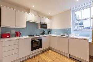 una cucina con armadi bianchi e un apparecchio rosso di Marylebone Apartments a Londra