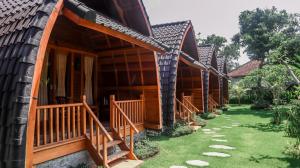 a row of cottages with wooden stairs and grass at Lumbung Temu Homestay in Ungasan