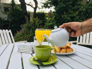 una persona sosteniendo una tetera y una taza en una mesa en San Remo Punta Hotel en Punta del Este