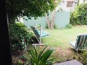 a yard with two lawn chairs and a blue fence at San Remo Punta Hotel in Punta del Este