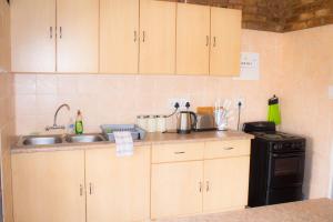 a kitchen with wooden cabinets and a sink and a stove at Stone Circle Cottage in Lydenburg +7 photos