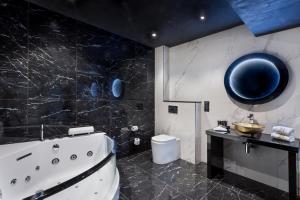 a bathroom with a tub and a toilet and a mirror at H Hotel & SPA - Adults Only in St. Julianʼs
