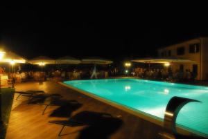 a swimming pool at night with chairs and umbrellas at Portasirena Agriturismo in Paestum