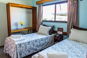 a hotel room with two beds and a window at Pousada Paraiso in Guanambi