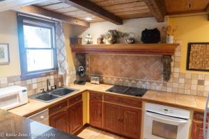 cocina con armarios de madera, fregadero y ventana en Flowertown Bed and Breakfast en Summerville