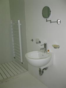 Baño blanco con lavabo y espejo en Family Hotel The Body, en Batak