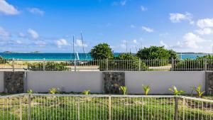 a fence with the beach in the background at Sea Front Apartment Orient Bay in Orient Bay French St Martin