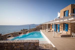 a house with a swimming pool next to the water at Villa Choulakia in Mikonos