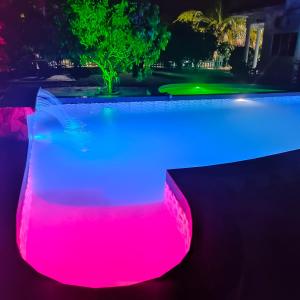 波德申的住宿－PD貝斯特度假屋，游泳池在晚上有粉红色和蓝色的灯光