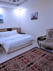 een slaapkamer met een bed, een stoel en een tapijt bij روائع الأحلام للاجنحة الفندقية in Jeddah