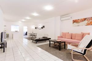 uma sala de estar com um sofá rosa e cadeiras em Driopon Apartment - Penthouse em Atenas