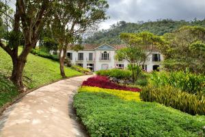 um jardim em frente a uma casa branca com flores em Casa Marambaia Hotel em Petrópolis
