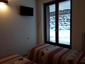 サンタ・カテリーナ・ヴァルフルヴァにあるApartments "STELLA ALPINA"のベッドルーム1室(ベッド1台付)、雪が降り注ぐ窓が備わります。